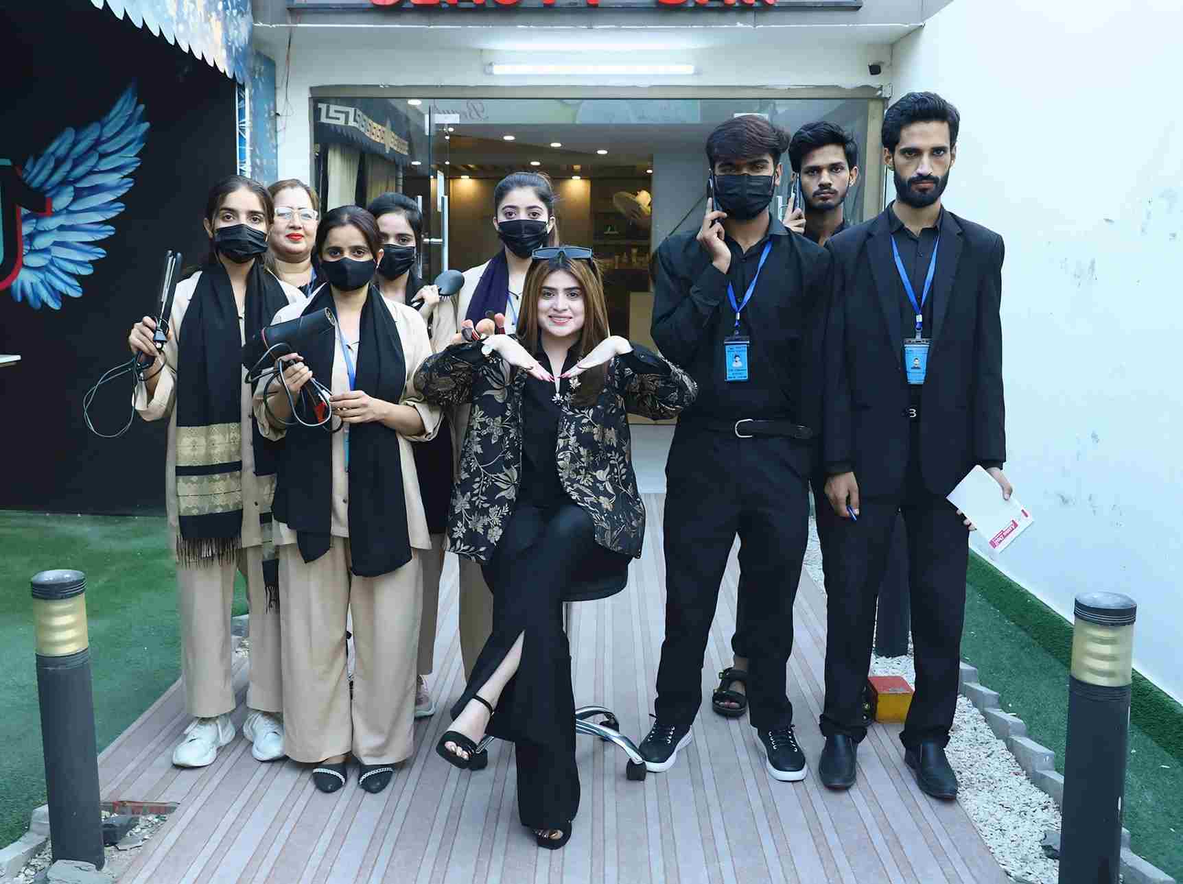 Professional salon staff and stylists posing outdoors in front of a beauty salon.